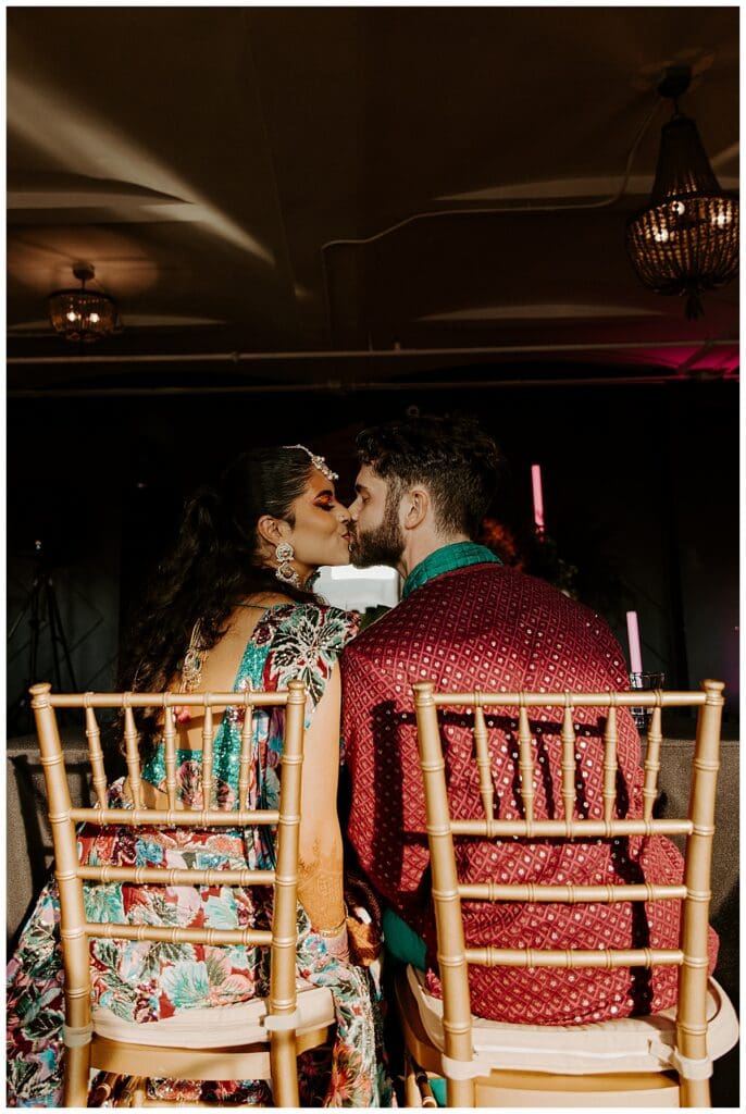 Aarushi and Shane sharing a kiss at their sweetheart table during the sangeet at the Lumber Exchange Minneapolis