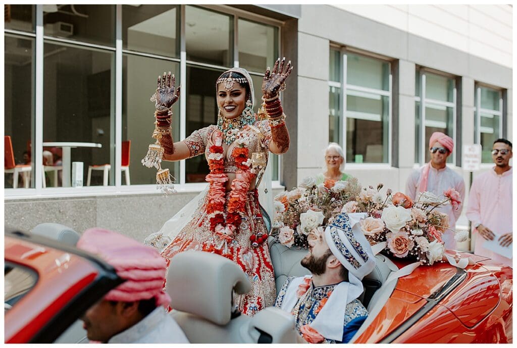 Aarushi and Shane in a red convertible after the baraat procession outside Mosaic Venue in Minneapolis