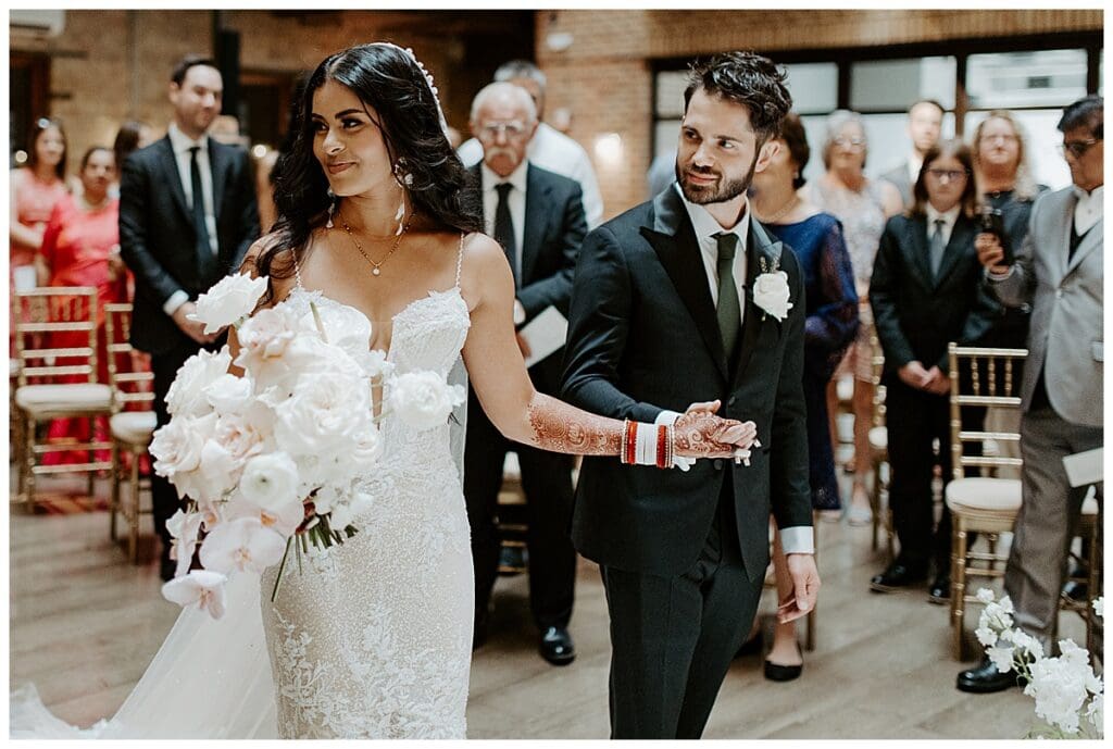 Aarushi walking down the aisle with Shane at the Christian wedding ceremony at the Lumber Exchange Minneapolis