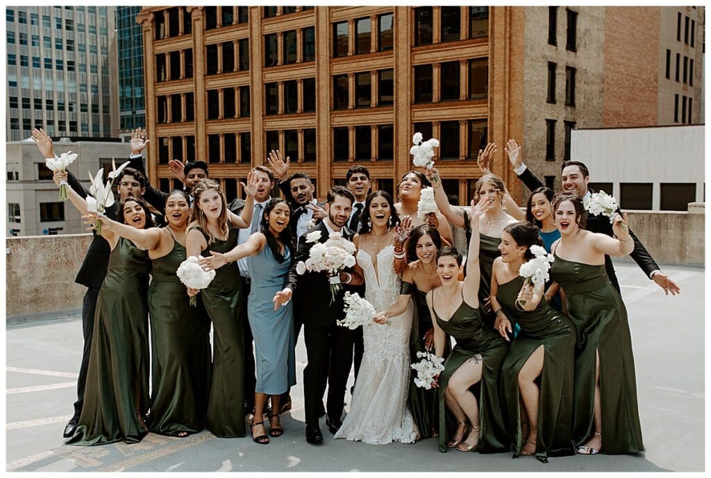 Aarushi with her bridesmaids in sage green dresses on the rooftop of the Lumber Exchange Minneapolis