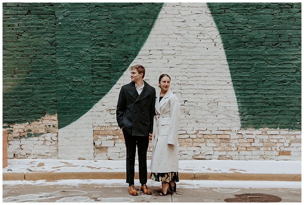 Meredith and Alec standing together in front of a mural during their Minneapolis City Hall engagement session