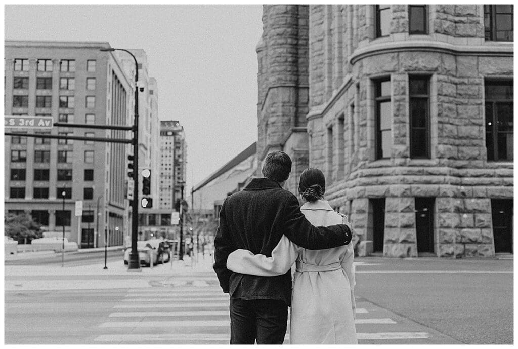 Black and white photo of Meredith and Alec walking through downtown Minneapolis during their engagement session