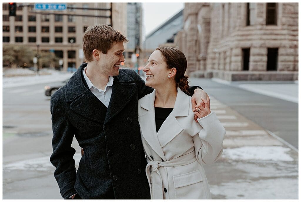 Meredith and Alec laughing together on the streets of downtown Minneapolis during their engagement session